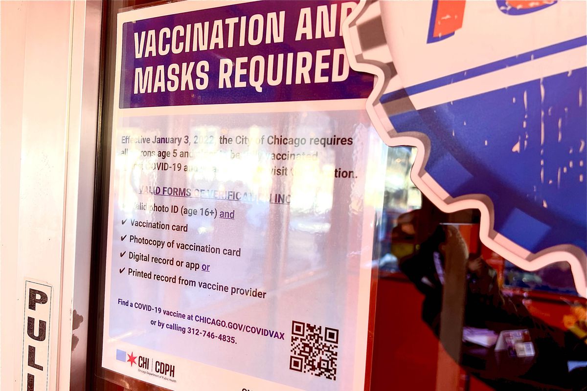 A sign reading “Vaccination and Masks Required” on a restaurant door