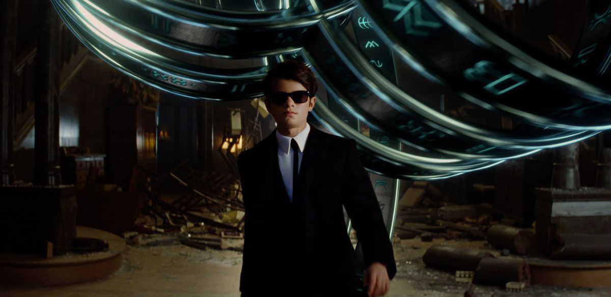 a tween boy in a black suit and sunglasses (Ferdia Shaw) walking toward the camera in Artemis Fowl