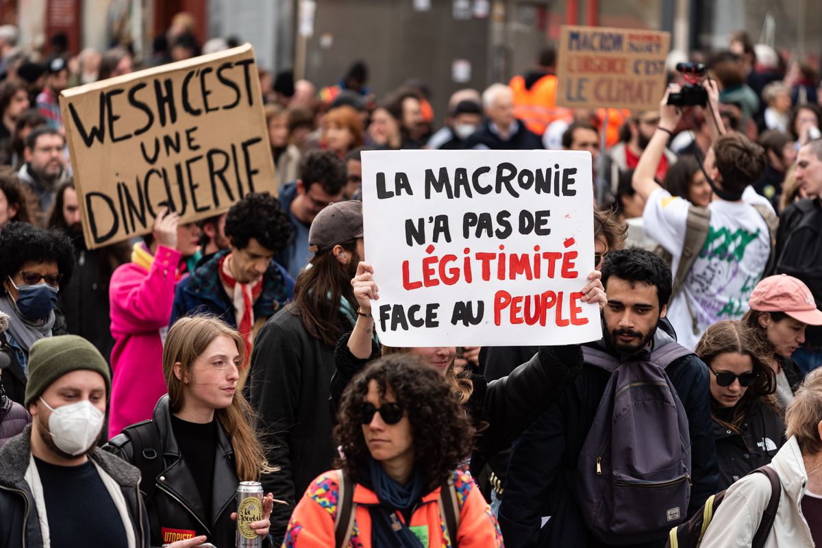 A&nbsp;demonstrator holds a sign that reads ‘’Macronie has no legitimacy in front of the people’’ at a demonstration that brought together several thousand people at the call of the intersyndicale, composed of all employee unions and youth organizations, on March 23, 2023, in Paris. The protest was against the adoption without a vote of the pension reform aimed at pushing back the retirement age from 62 to 64 years.