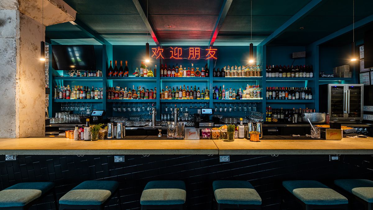 The main bar at Bar Chinois has a neon with Chinese characters that spell out, “Welcome friend.”