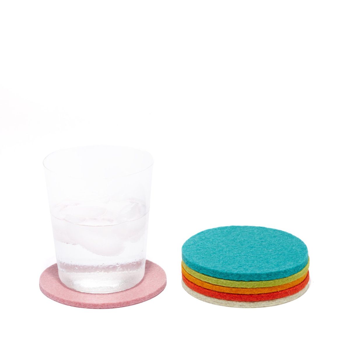 A stack of multicolored coasters next to a pink coaster with a water glass on top