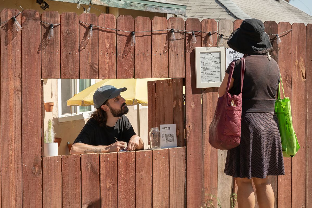 A man behind a fence taking a customer’s order at the Narwal pop-up.