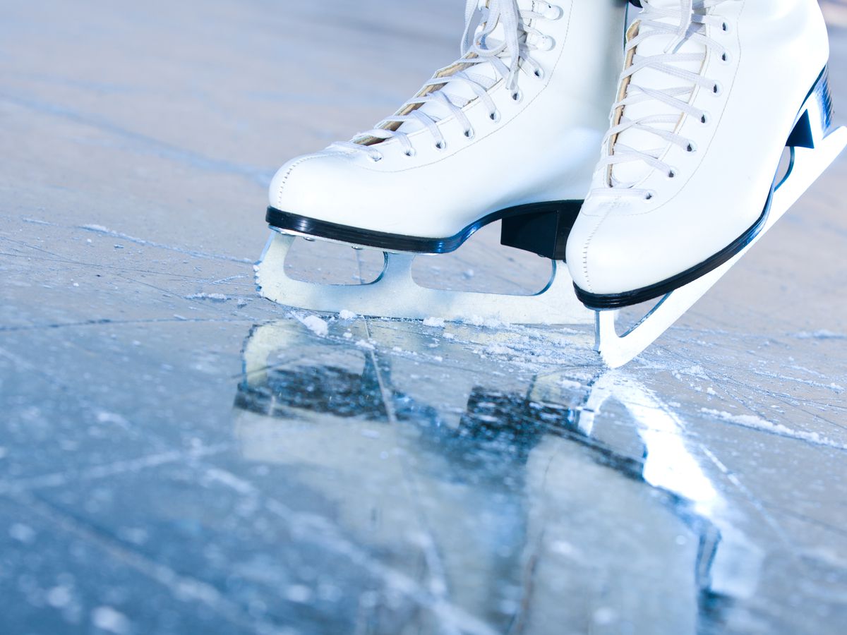 A pair of ice skates shown on ice.