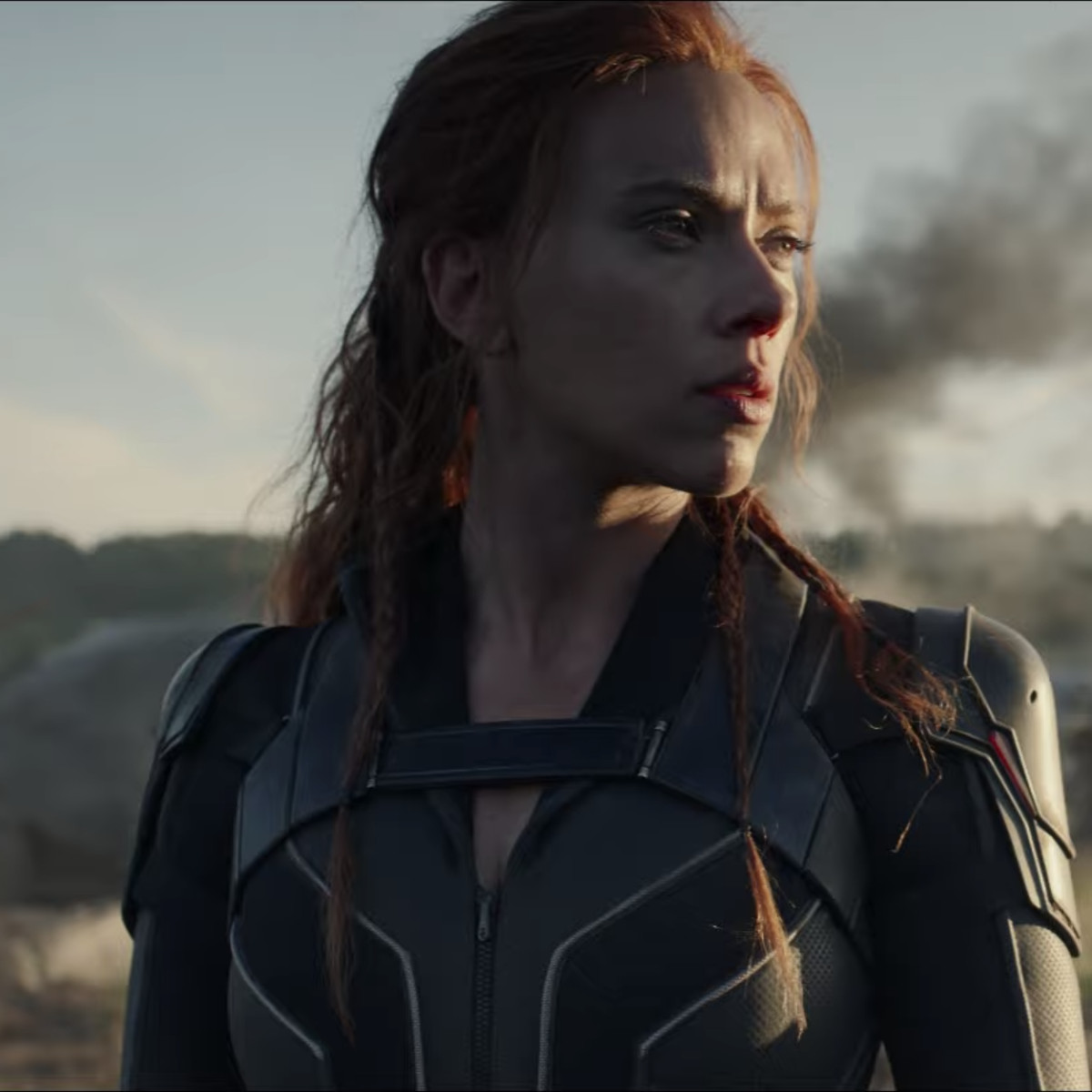 Scarlett Johansson as Natasha Romanoff/Black Widow looks cool posing in front of some smoke in a field, in a teaser trailer for Marvel Studios’ Black Widow.