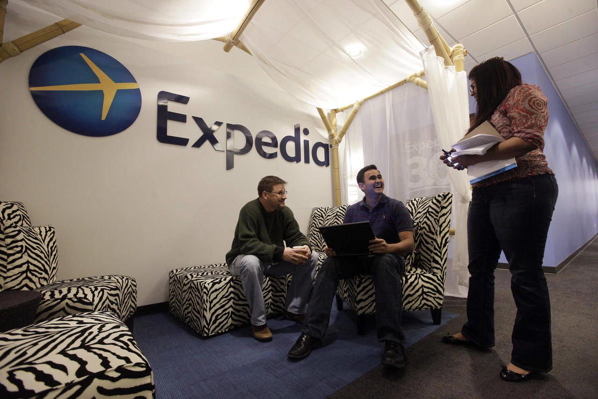 In this Tuesday, Jan. 15, 2013, file photo, Expedia analytics team workers Mike Brown, left, Saurin Pandya and Prashanti Tata chat in an alcove set up for employees, in Bellevue, Wash. Expedia announced on Thursday, Feb. 12, 2015, that it is buying rival 