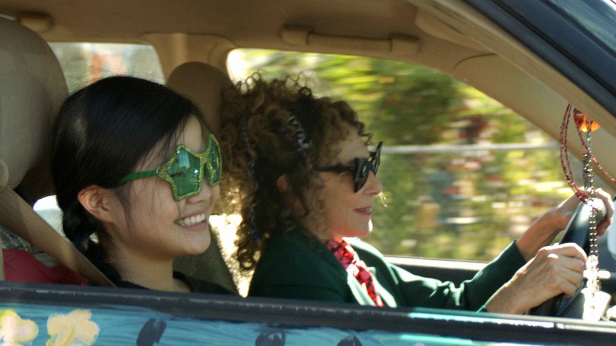 a girl with star-shaped glasses riding in a car with an older woman
