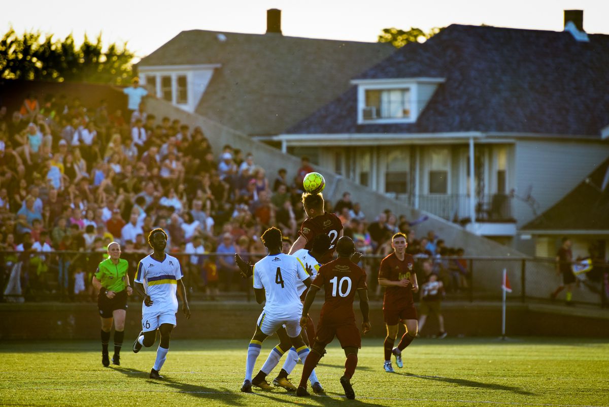 A soccoer player strikes a header in a crowded group