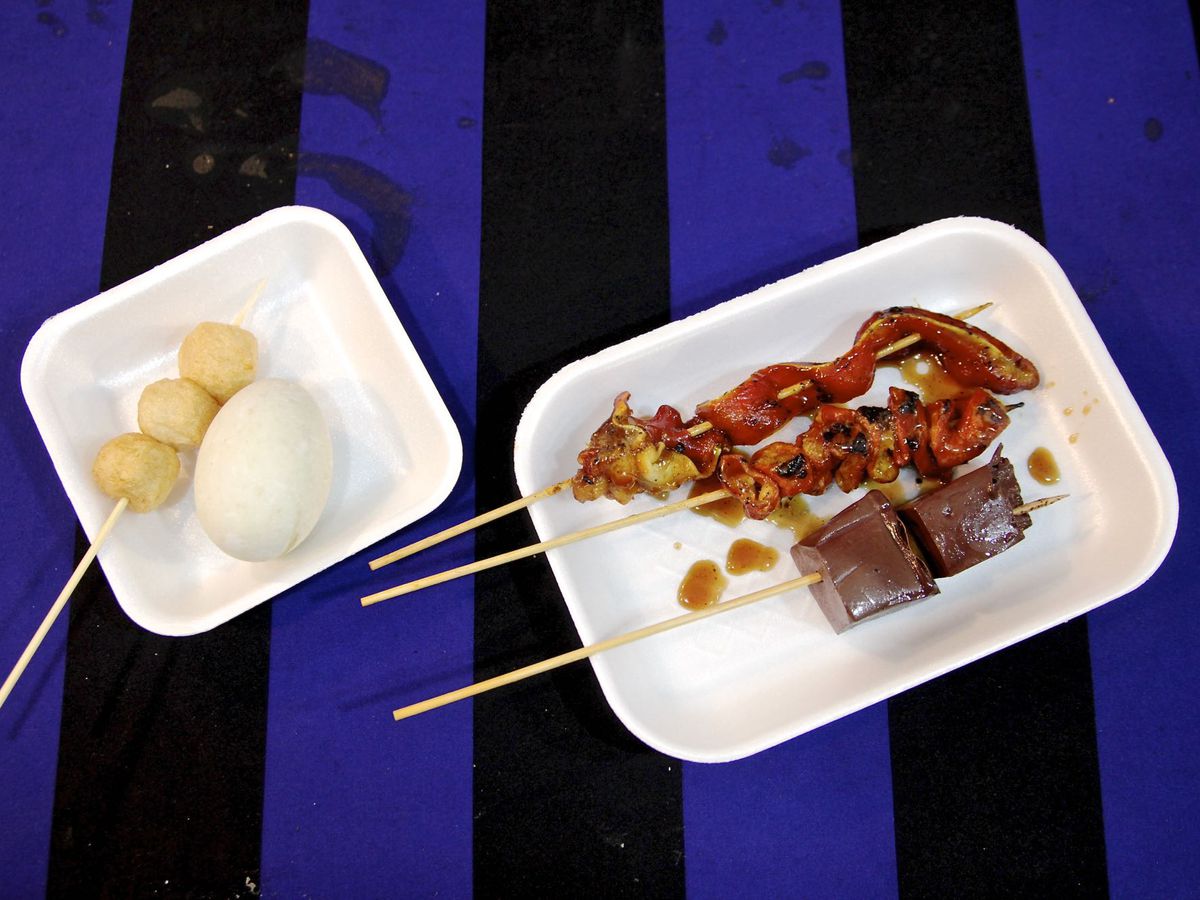 A blue striped table holds plates of meat skewers.