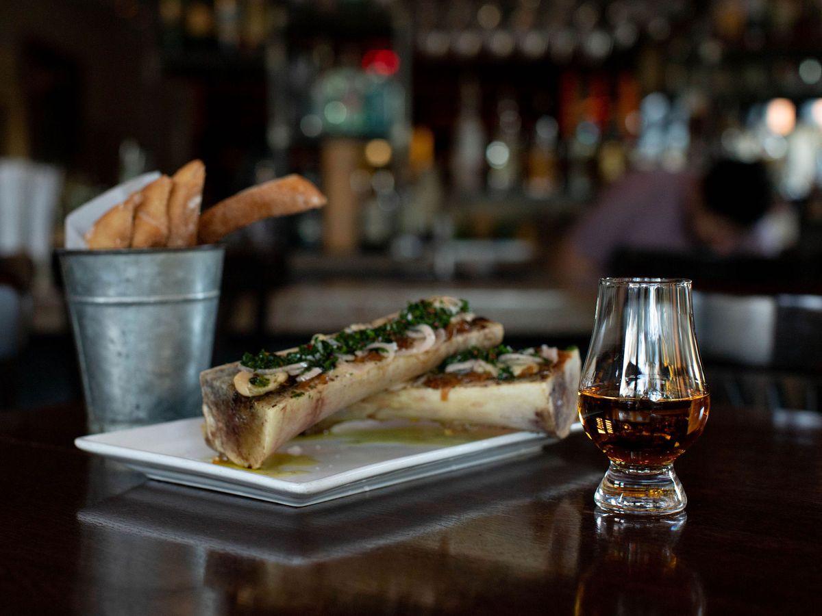 A plate of bone marrow and french fries next to a glass of Highland Park whisky.