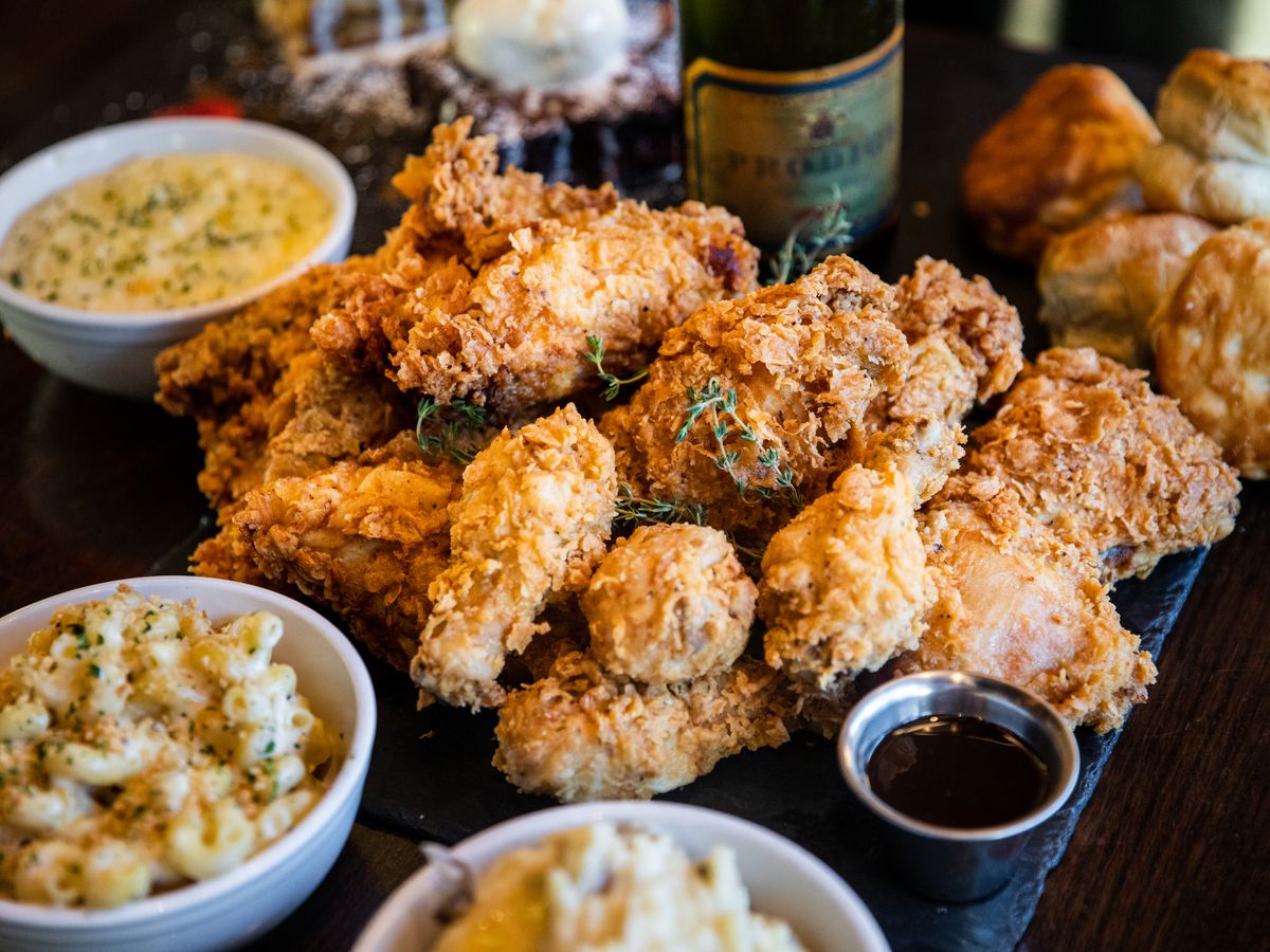 A spread of fried chicken and sides of mac and cheese, mashed potatoes, and biscuits with a side of syrup at Max’s Wine Dive.
