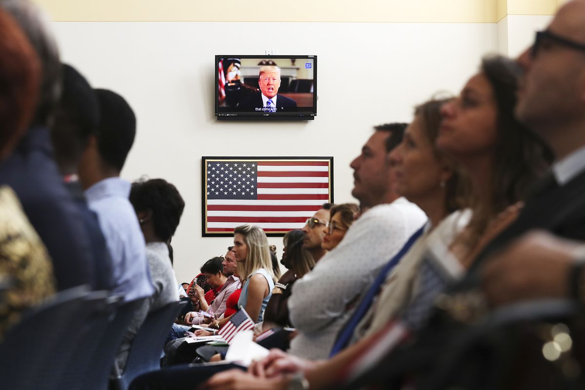 President Trump is seen on a television screen addressing new US citizens.