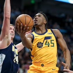 Utah Jazz guard Donovan Mitchell (45) lays it up ahead of Denver Nuggets center Mason Plumlee (24) at Vivint Smart Home Arena in Salt Lake City on Tuesday, Nov. 28, 2017.