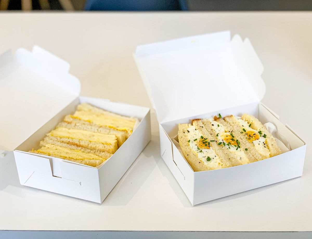 Two egg sandwiches, one an omelette style, the other an egg salad, in side by side boxes.