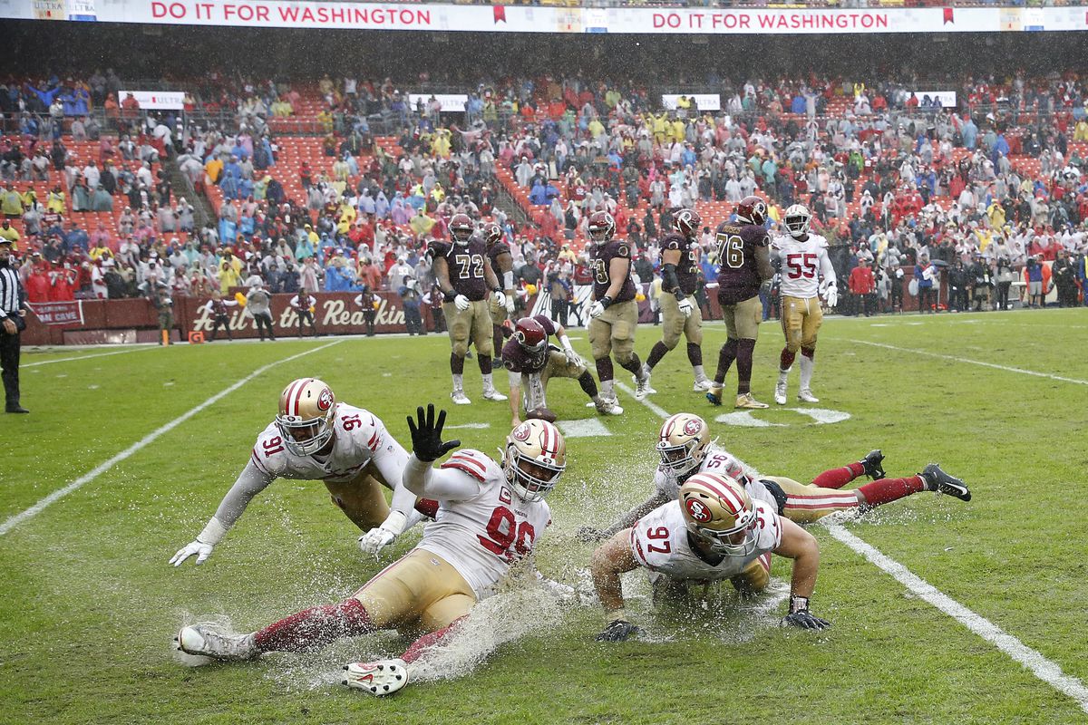 San Francisco 49ers defensive end Arik Armstead, defensive tackle DeForest Buckner, defensive end Nick Bosa, and middle linebacker Kwon Alexander celebrate by sliding on the wet field after the final play against Washington at FedExField.