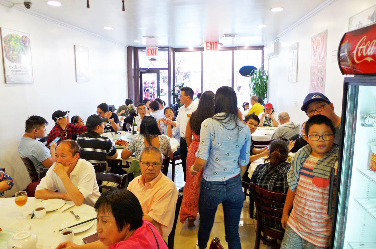 Several tables are filled with diners of all ages, as a youngster with glasses peeps around the soda cooler...
