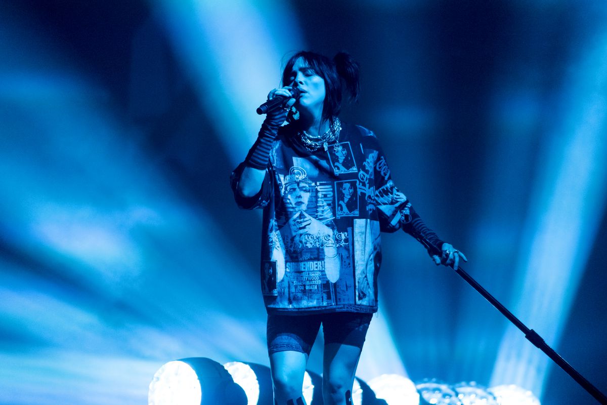 Billie Eilish performing at Glastonbury Festival with blue lights behind her