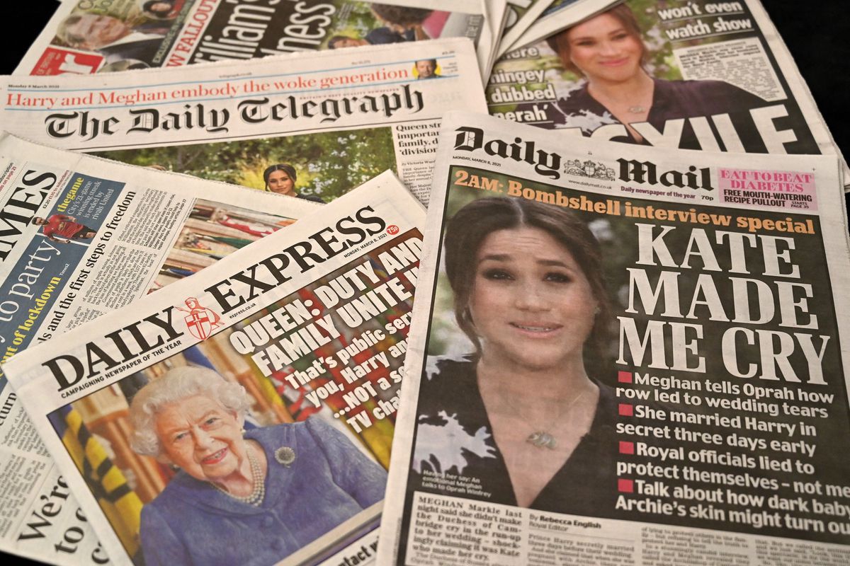Tabloid covers of Meghan Markle and the Queen lie scattered.