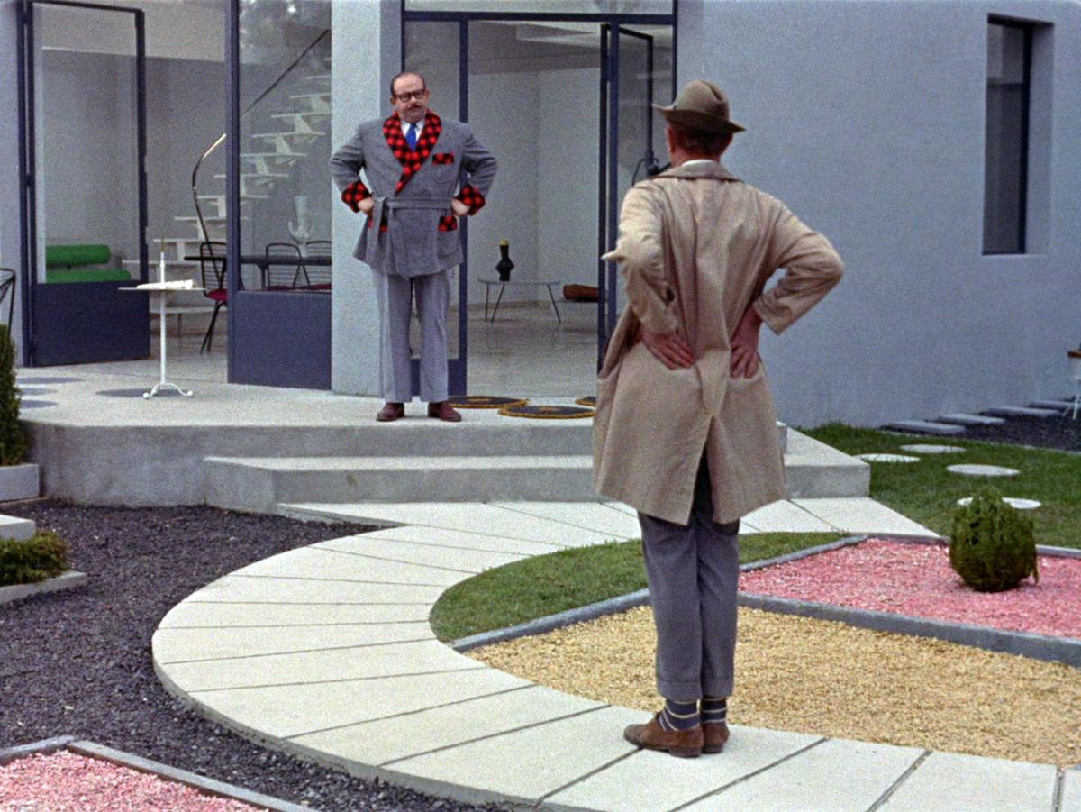 Monsieur Hulot with his hands on his hips starring at an irritated man in a modernist garden in Mon Oncle.