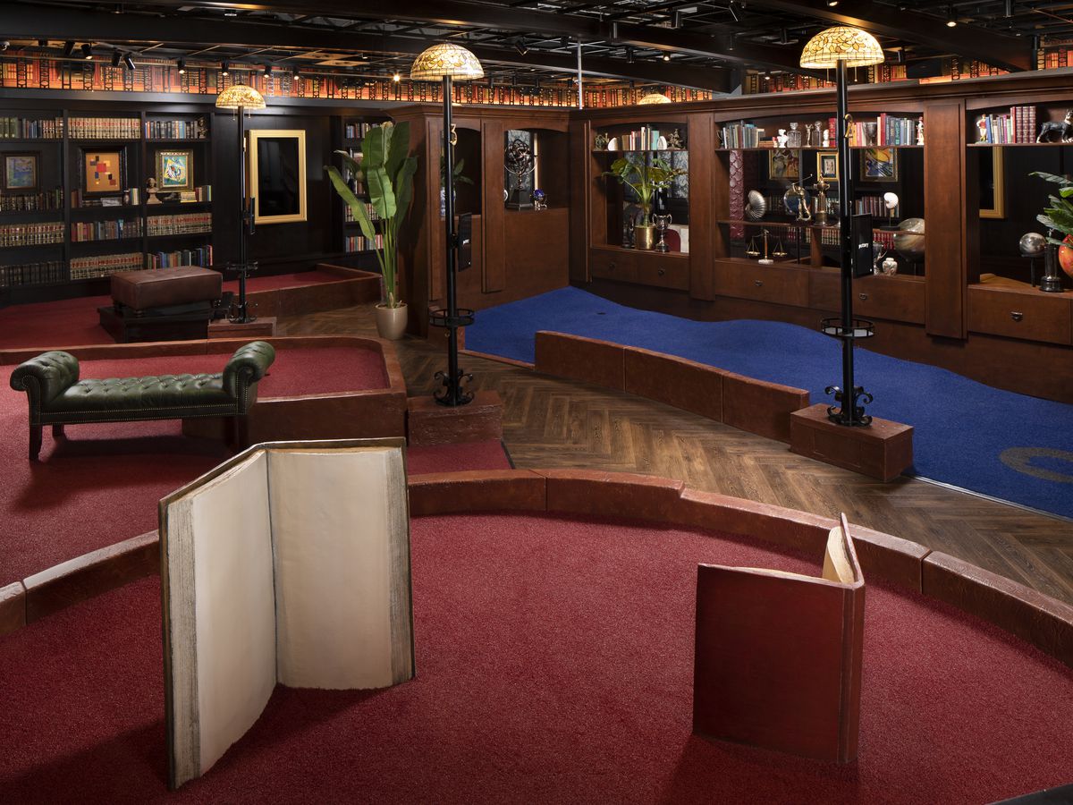 Puttery Houston’s library-themed room with book shelves, lounge chairs, and dim lighting.