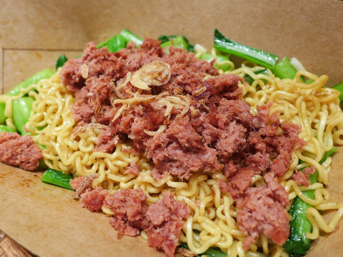Curly noodles with shredded red meat on top and chopped greens underneath.