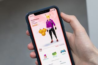 Ръката държи iPhone, играещ Pokemon Go, показва екрана на профила на играча