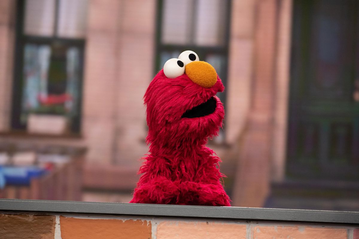 A photo of Elmo the puppet from Sesame Street on the Today Show. He is sitting behind a desk as he looks to the side. 