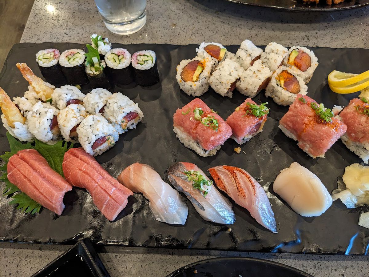 A mix of rolls and nigiri on a slate plate. 