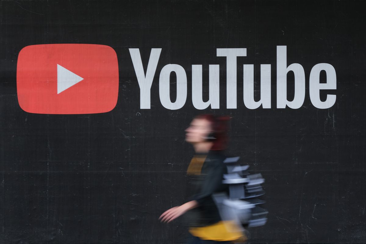 A young woman wearing headphones walks past a billboard advertisement for YouTube on September 27, 2019 in Berlin, Germany.
