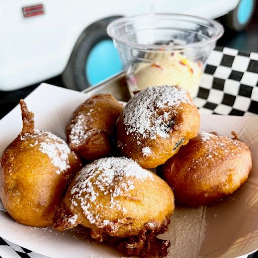 Five fried Oreos dusted with confectioner sugar with a side of vanilla ice cream. 