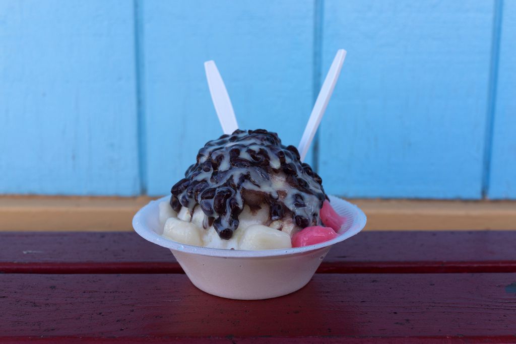 A plastic cup of shaved ice with oozing chocolate topping
