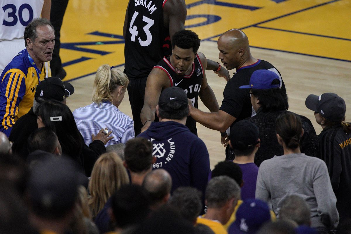 Toronto Raptors guard Kyle Lowry, middle, gestures next to referee Marc Davis (8) near the front row of fans during the second half of Game 3 of basketball's NBA Finals between the Golden State Warriors and the Raptors in Oakland, Calif., Wednesday, June 