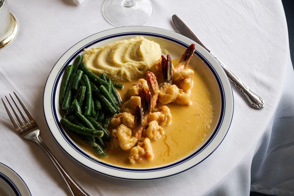 Battered shrimp served in a light yellow sauce at a white tablecloth restaurant at daytime.
