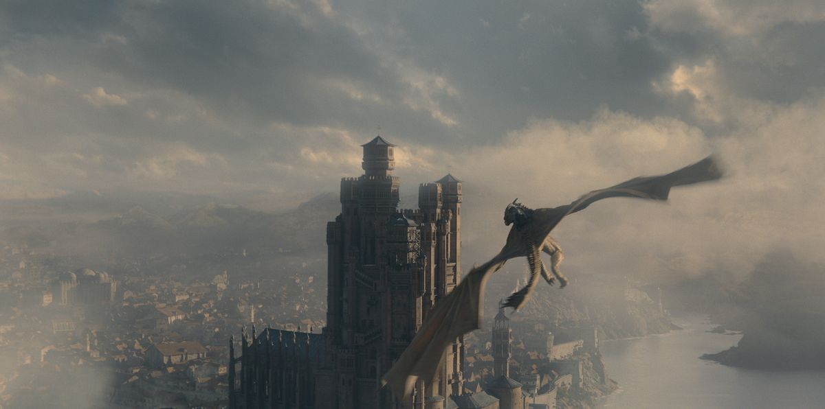 Syrax, a giant golden dragon, flies through the skies of King's Landing towards the Red Keep in House of the Dragon