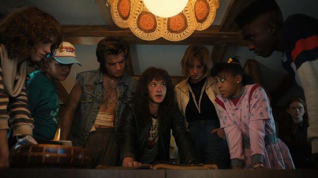 Characters gather round a table in Stranger Things 4