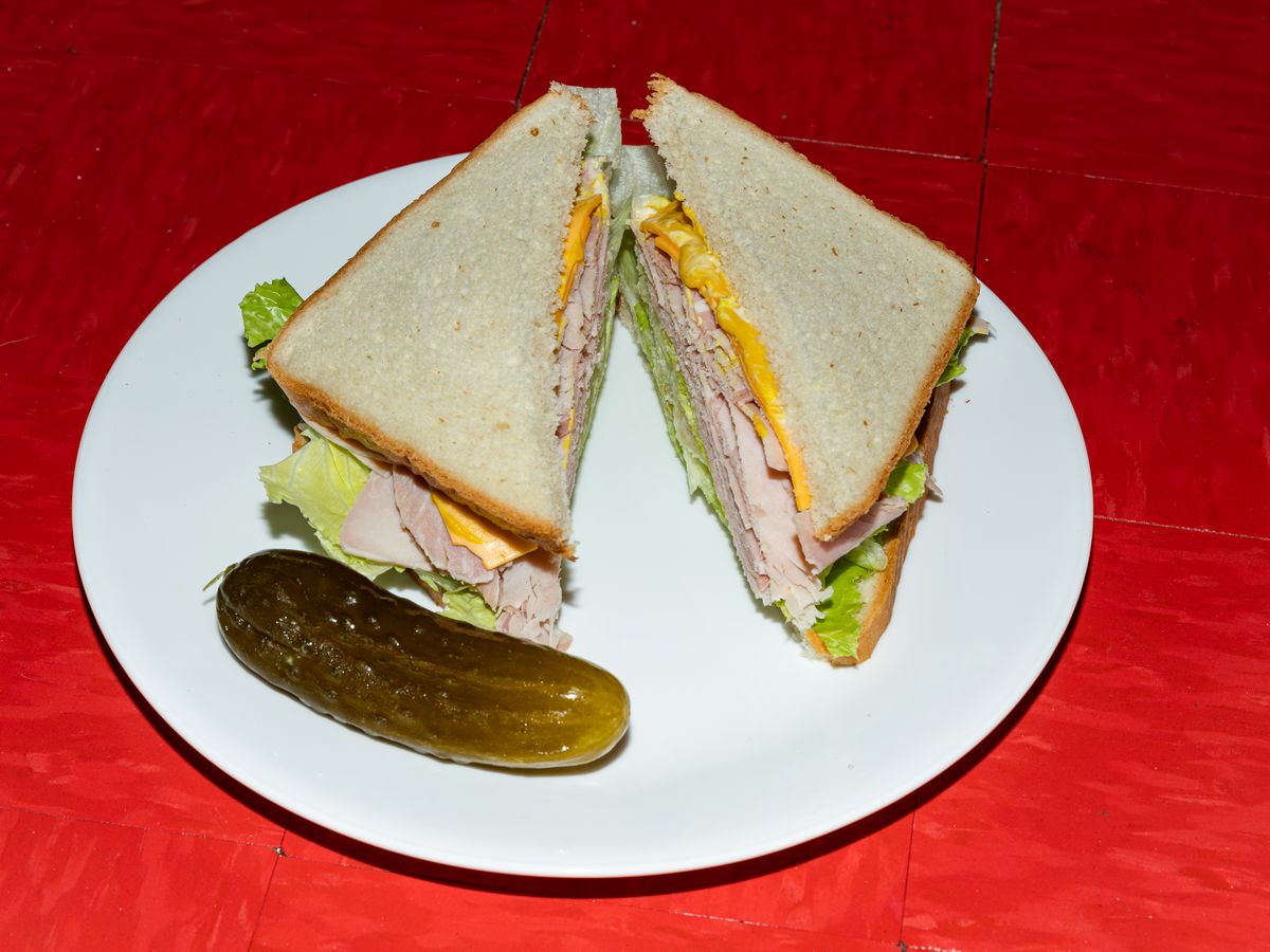 Ham, cheese, lettuce, and mayonnaise are arranged on white sandwich triangles.