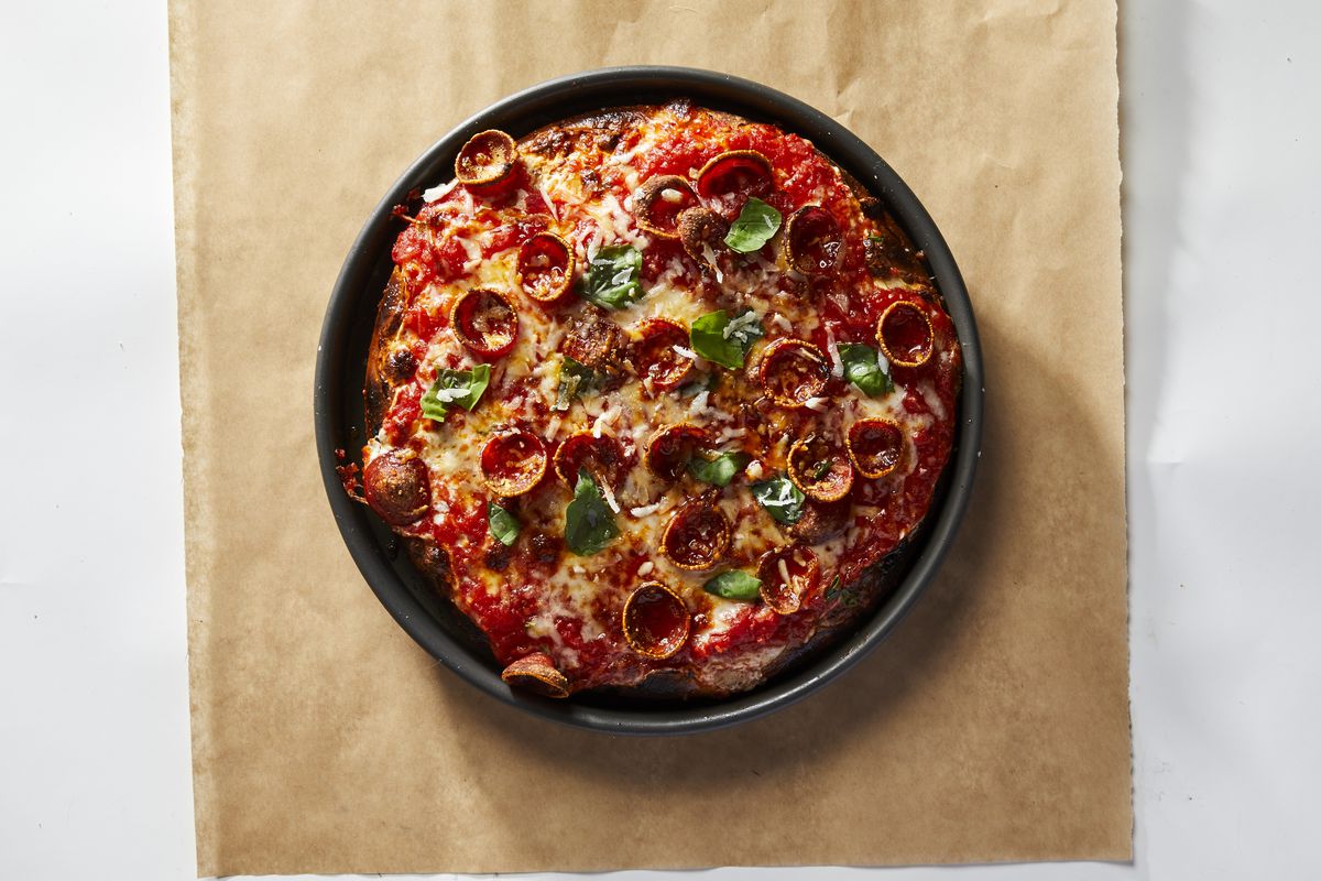 An overhead photograph of a round Sicilian-style pan pizza, topped with melty cheese and pepperoni
