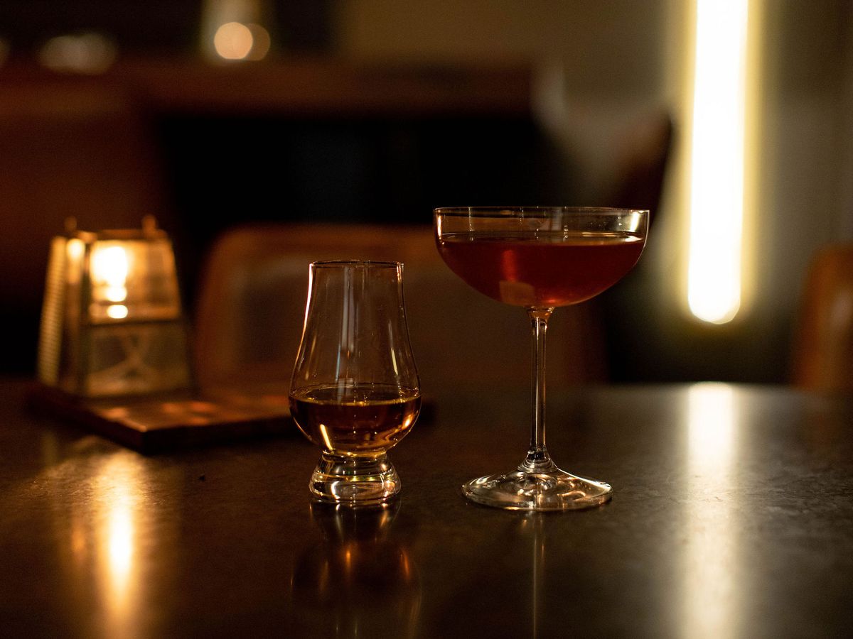 A glass of Highland Park whisky and a cocktail in a coupe glass.