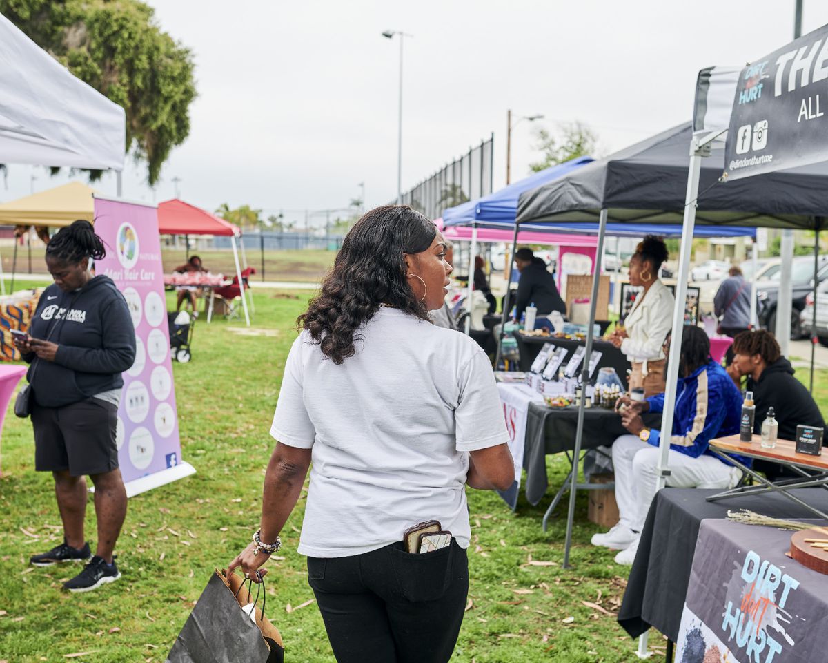 Shala Waines walks along a row of tents selling merchandise on a grassy field.