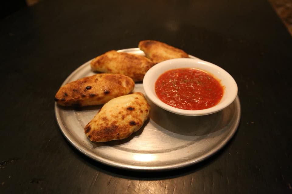 A plate of mini calzones with marinara sauce from the Chicago restaurant Pizzeria Serio.