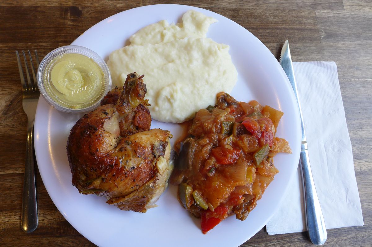 A white plate with chicken, ratatouille, and mashed potatoes.