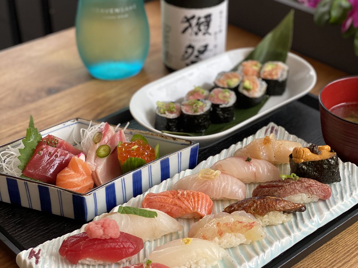 A variety of sushi on trays, atop a wooden table, from DOMODOMO New York restaurant. 