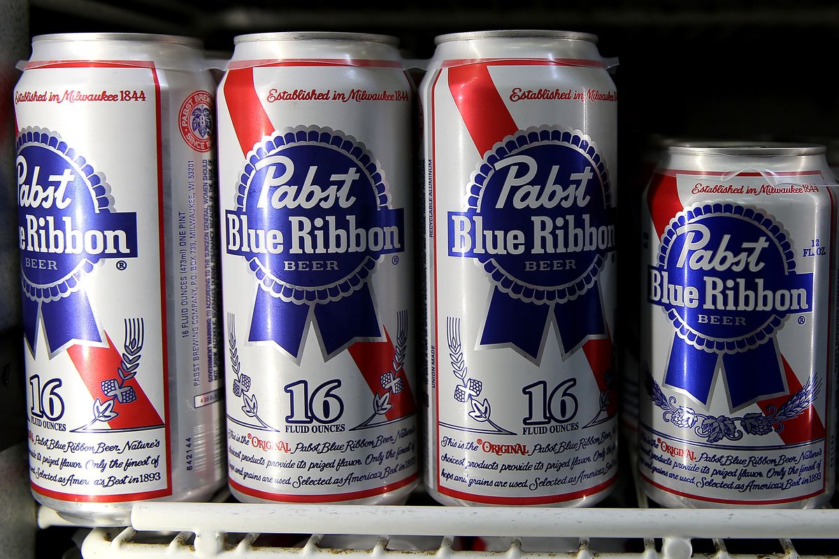Cans of Pabst Blue Ribbon beer sit on a shelf at a convenience store.