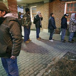 In this photo taken Feb. 3, 2010, homeless men and women stand in line to be searched before being bused to local churches serving as shelters  in Riverhead, N.Y.