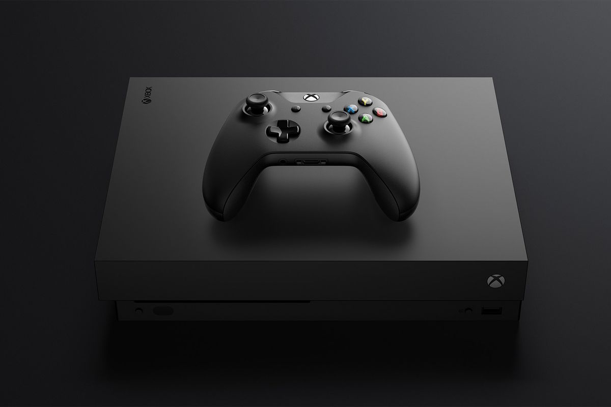 A photo of an Xbox One X console with an Xbox One controller resting on it top panel.