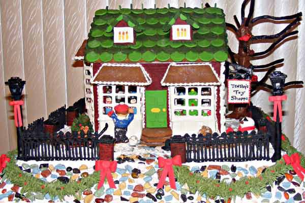 Gingerbread toy shop with a black fence surrounding it.