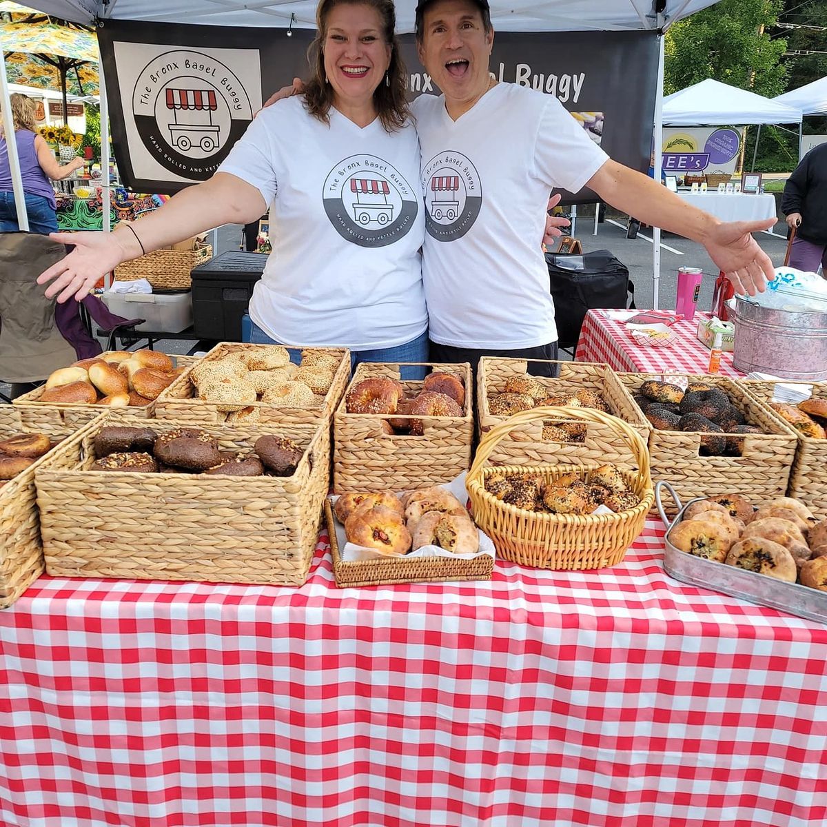 Julie Dragich and Steven Novotny in front of their table filled with bagels from the Bronx Bagel Buggy at the Brookhaven Farmers Market in Georgia.