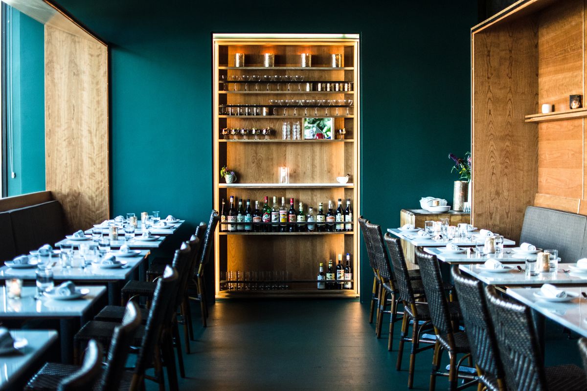 Interior of a small restaurant with dark teal walls and light wooden accents.