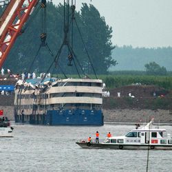 Medical workers make preparations near the capsized Eastern Star ship, as it is lifted by cranes on the Yangtze River in Jianli county of southern China’s Hubei province, as seen from across the river from Huarong county of southern China’s Hunan province, Friday, June 5, 2015. The Eastern Star's top-deck cabins with smashed blue roofs jutted out of gray water Friday after Chinese disaster teams righted the capsized river cruiser to ease the search for people still missing. 
