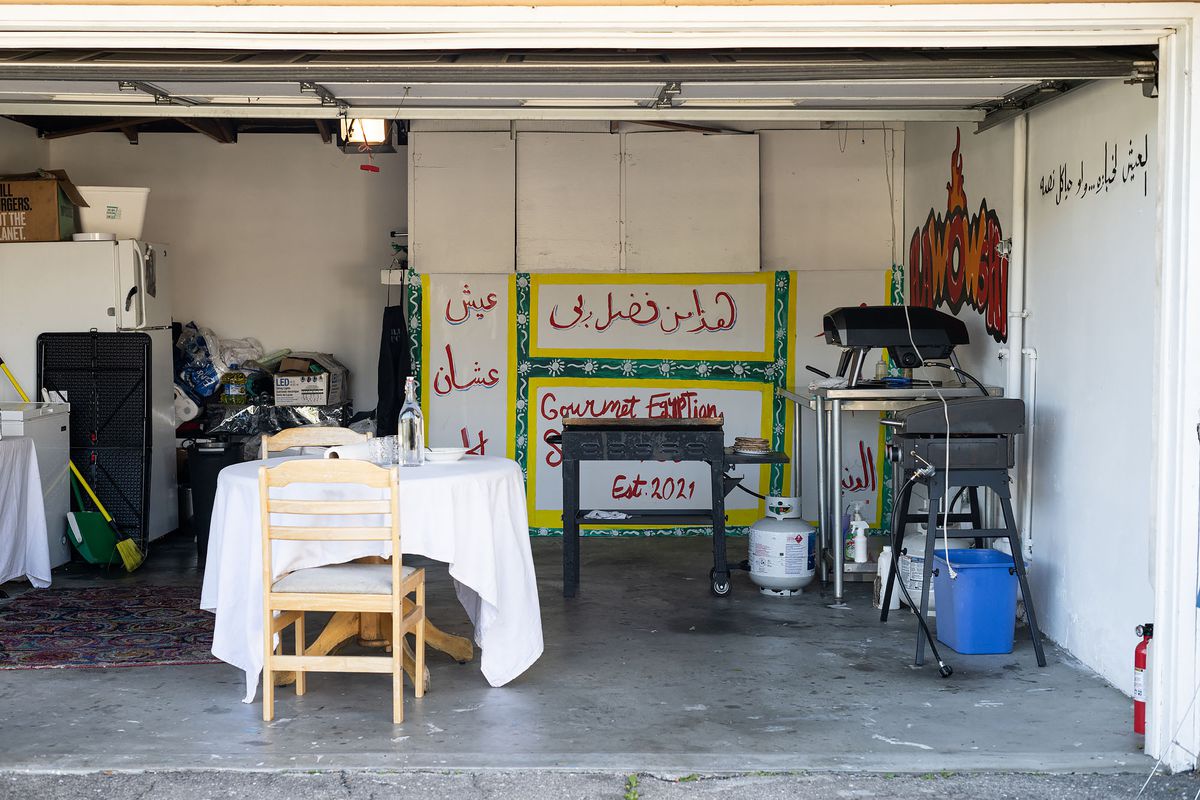 A wide look at a garage where a person pops up selling Egyptian food.