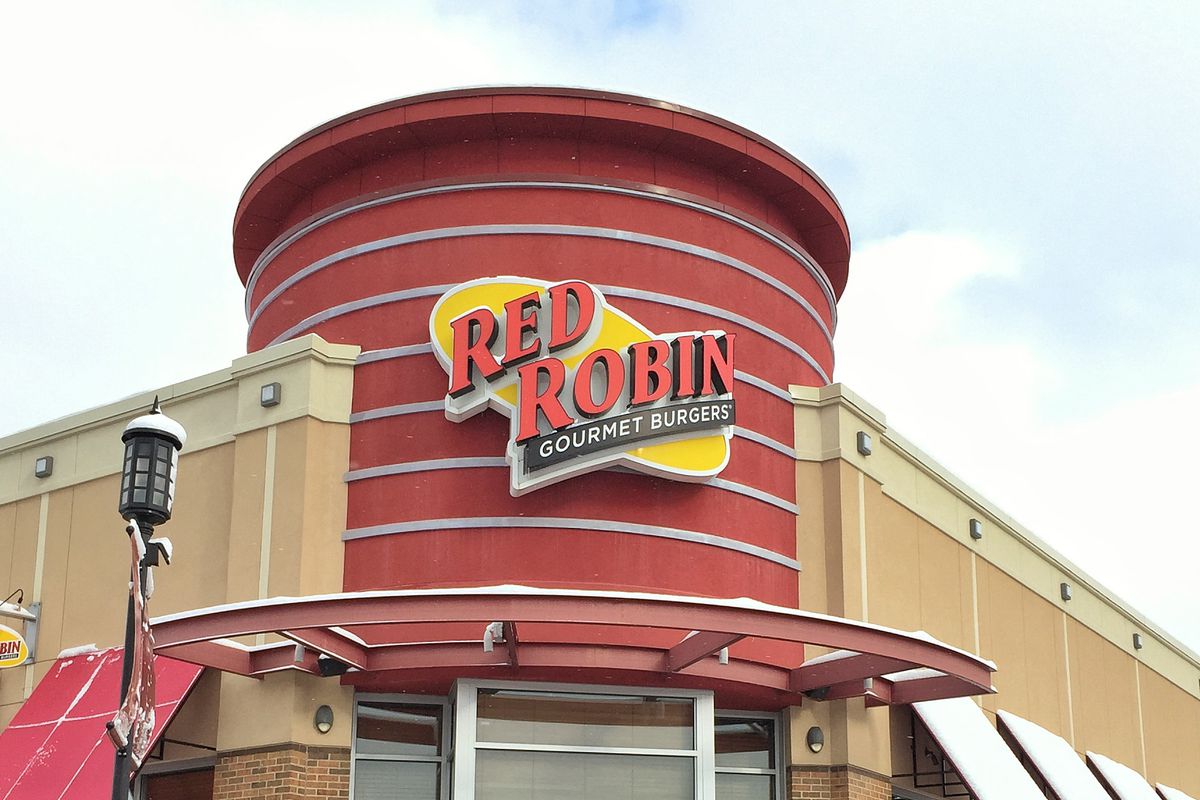 A Red Robin restaurant sign shown from the outside of a building on a cloudy day.  